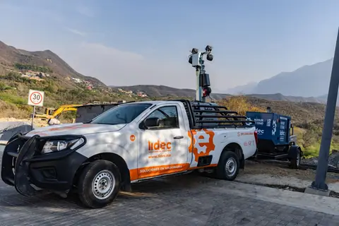 Nissan NP300 blanca con gráfico naranja de maquinaria en la sierra