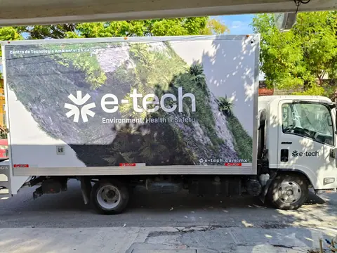 Costado de caja de camión Isuzu con wrap fotográfico de vegetación y logotipo