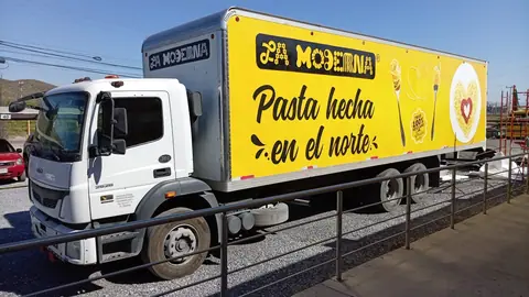 Camión con caja amarilla rotulada con gráfica de pasta, vista tres cuartos