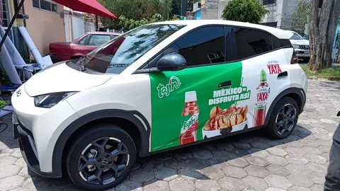 Hatchback BYD blanco con wrap parcial verde de salsa, vista lateral